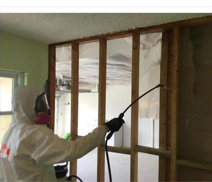 Technician wearing a white plastic suit to keep him protected while removing mold in a property